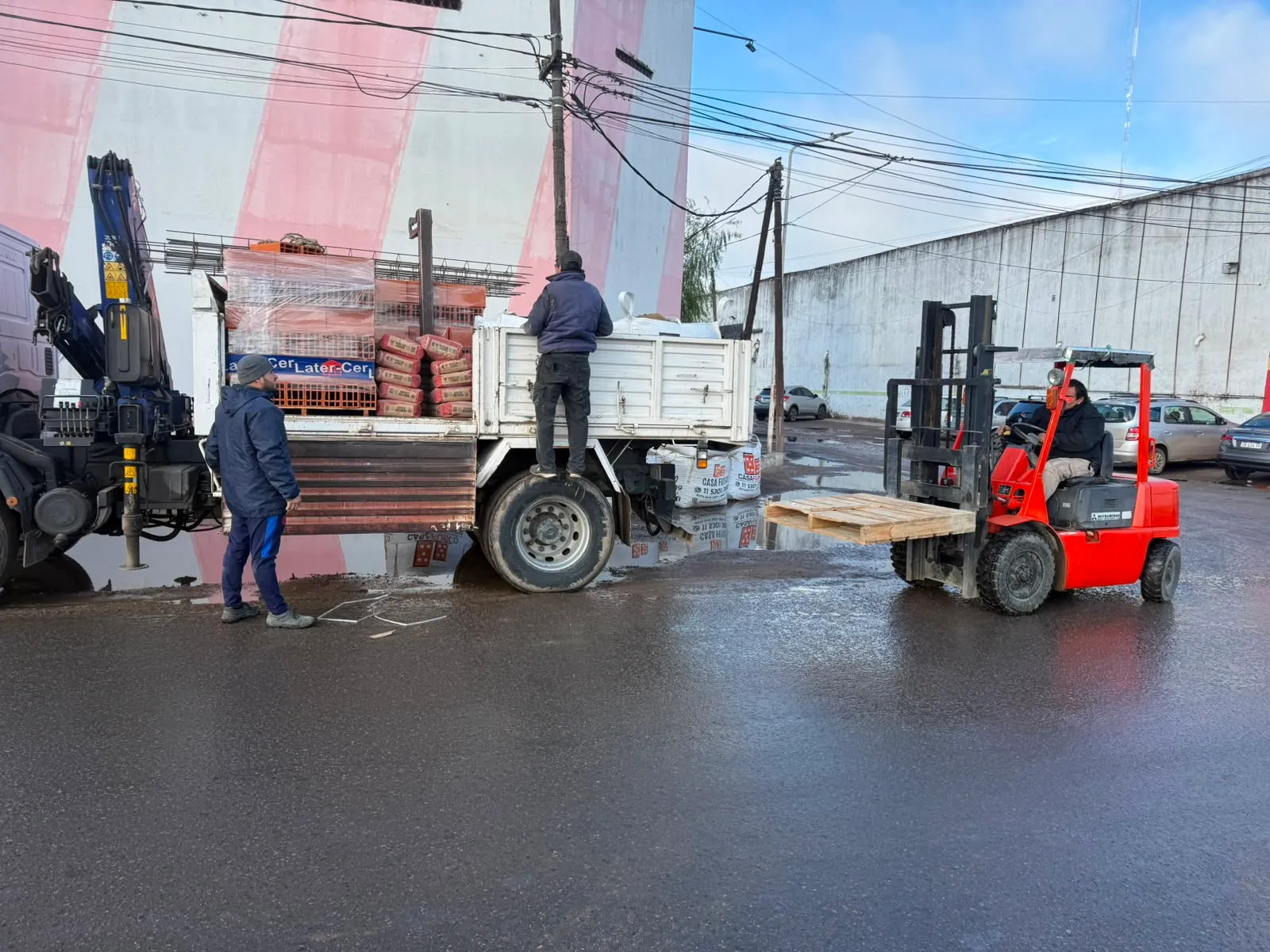 Equipo de Casa Fusco cargando un camión con pallets de ladrillos y cemento